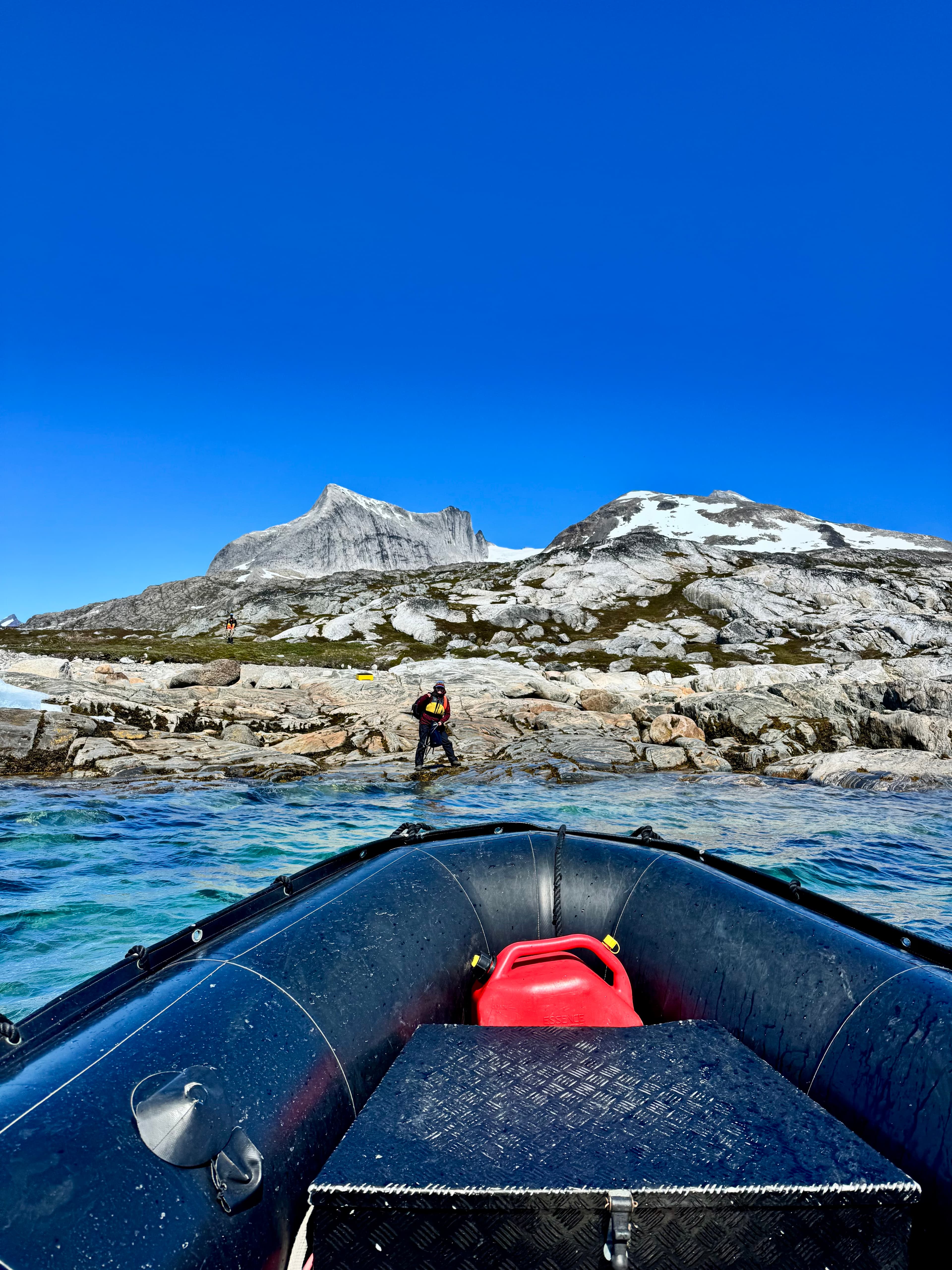 A small boat approaching the rocky Greenland coast